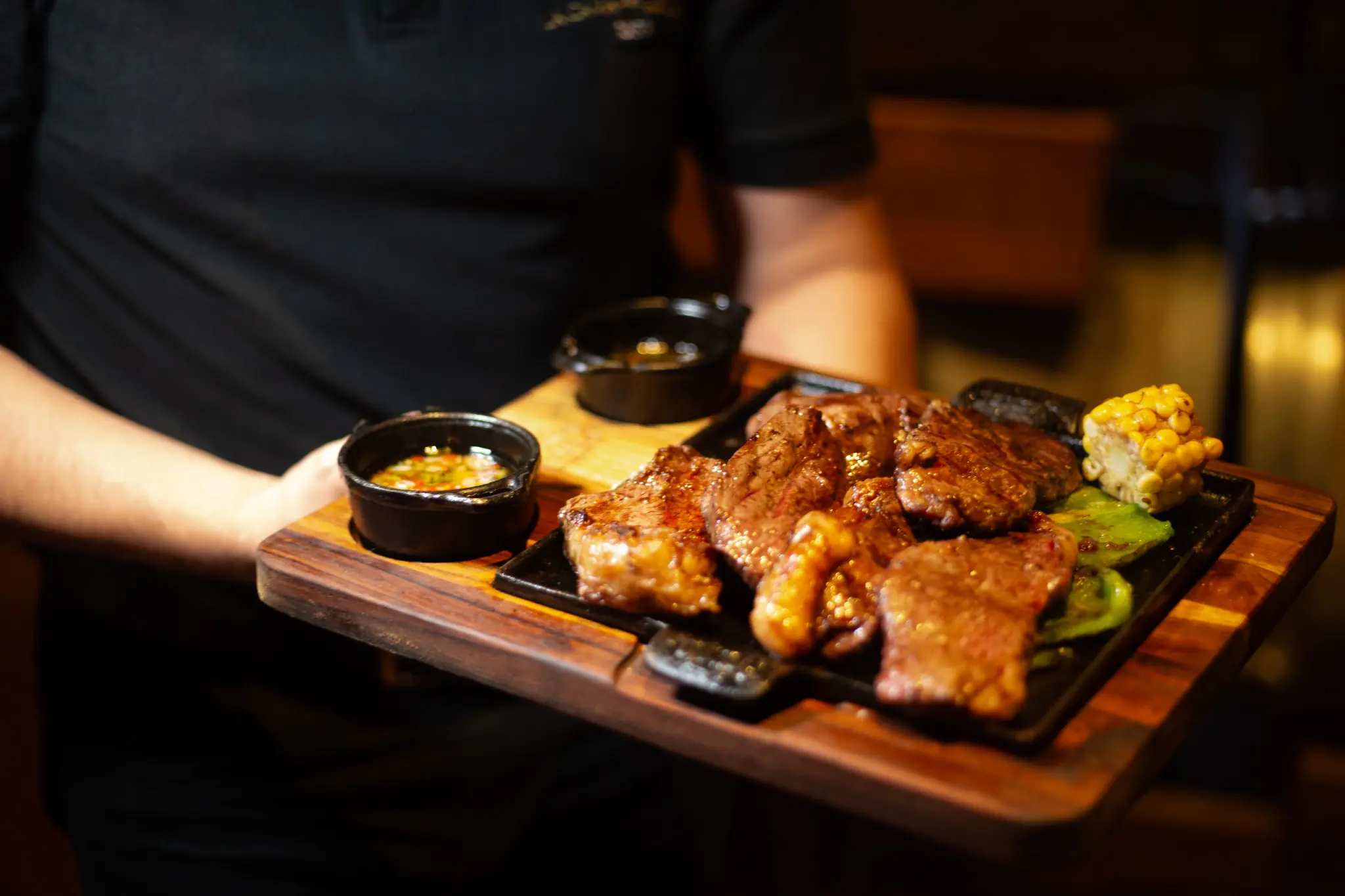 Tabla de cortes a la parrilla con choclo y salsas, servida en el salón